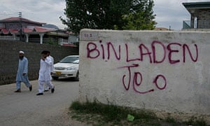 Pakistanis walk past graffiti translated as "long live Bin Laden" in Abbottabad.
