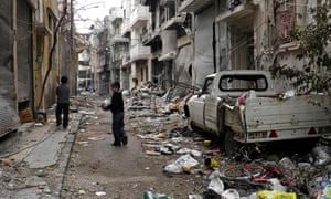 Children play on a street of damaged buildings in the besieged city of Homs