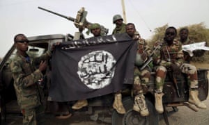 Nigerian soldiers hold up a Boko Haram flag seized in the retaken town of Damasak earlier this month.