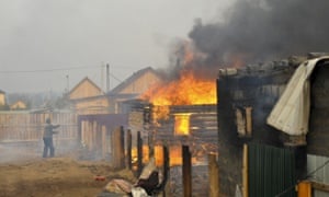 A man tries to save his home from blaze at neighbouring property in Smolenka, Siberia.