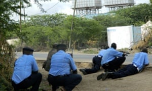 Kenyan police officers take cover outside the Garissa University College during an attack by gunmen.