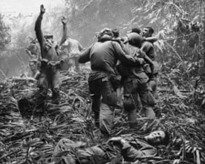 As fellow troopers aid wounded comrades, a paratrooper of A Company, 101st Airborne Division, guides a medevac helicopter through the jungle foliage to pick up casualties suffered during a five-day patrol near Hue, April 1968