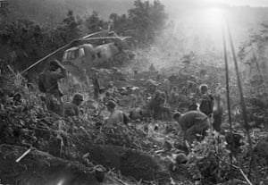 Marines emerge from their foxholes south of the DMZ after a third night of fighting against North Vietnamese troops, September 1966. The helicopter at left was shot down when it came in to resupply the unit