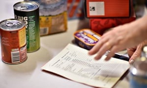 A volunteer selects food for a visitor's order at a foodbank charity in west London