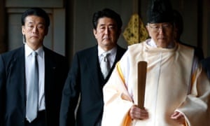Shinzo Abe is led by a Shinto priest as he visits Yasukuni shrine in December 2013