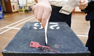 A voter places his voting card into a ballot box