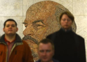 Subway passengers walk past a huge portrait of the Soviet Union founder Vladimir Lenin in a vestibule of the Biblioteka Imeni Lenina metro station in Moscow.