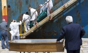 The body of a dead migrant is carried from a cargo ship as it arrives in the Sicilian port of Catania.