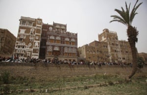 People gather to look at houses destroyed by Saudi air strikes in the old city of Sana’a, Yemen