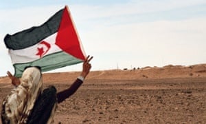 A girl from Western Sahara flies a Sahrawi flag in front of the Moroccan Wall in 2011.