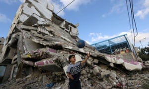 A Palestinian boy plays football outside the remains of his house in Gaza City that was destroyed during the summer 2014 war.