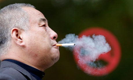 A man smokes next to a "No Smoking" sign in downtown Shanghai