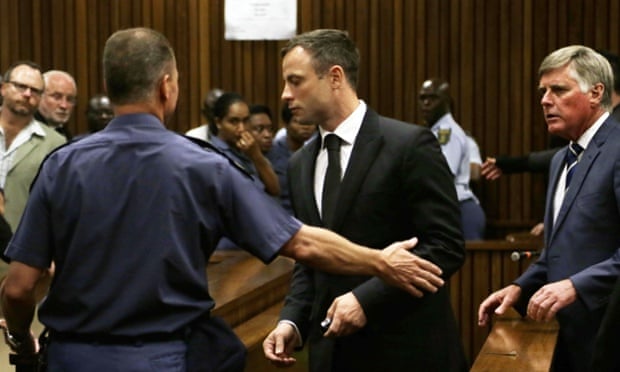 Oscar Pistorius is lead by an officer into a holding cell after being sentenced.