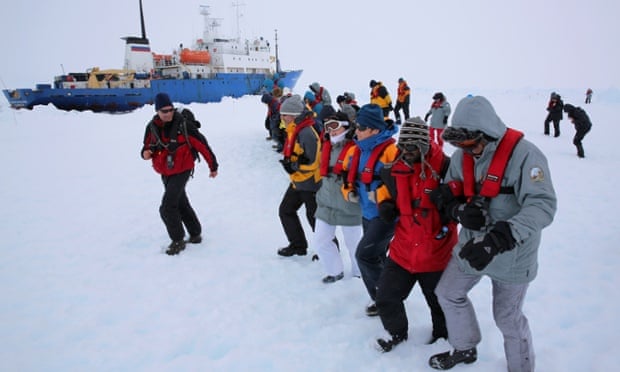 Passengers and scientists stomp an area of ice next to the Akademik Shokalskiy for a makeshift helicopter landing pad in readiness for evacuation from the trapped ship in Antarctica.