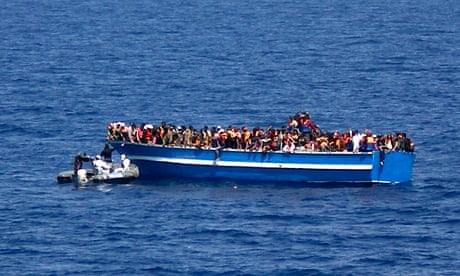 An Italian navy motorboat approaches a boat of migrants in the Mediterranean Sea
