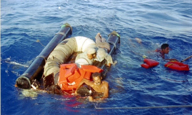 In this 11 September 1994 photo, three refugees cling to their overturned raft and life preservers as the US coast guard moves in to pick them up approximately 15 miles north of Cuba. 
