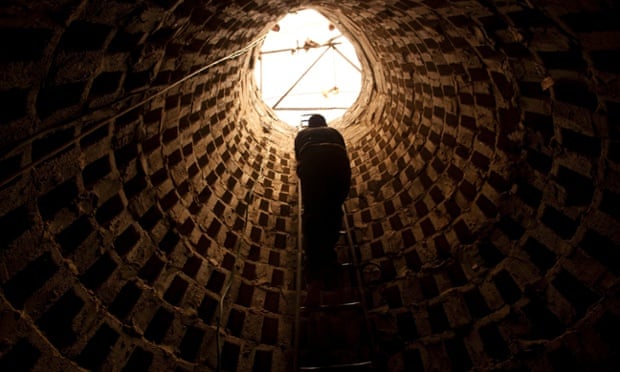 A Palestinian climbs out of a tunnel