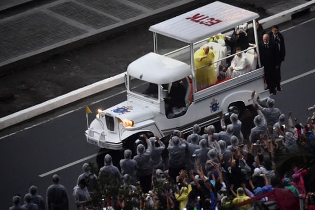 Pope Francis waves to the crowd from  his popemobile based on the design of a jeepney.
