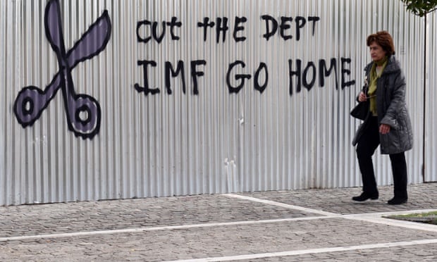 A woman walks past a slogan in central Athens.