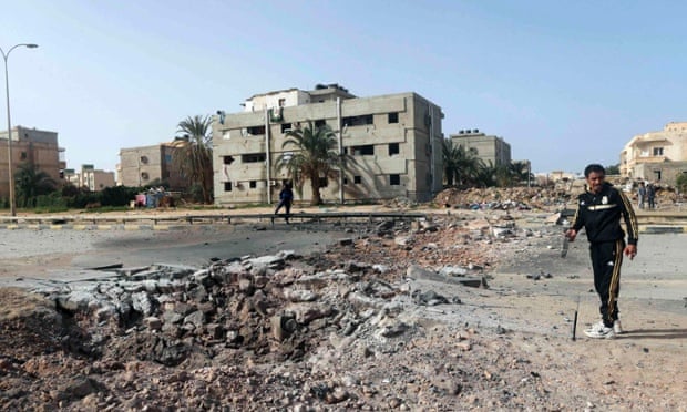 People stand near the site of an explosion in Benghazi. A car laden with explosives killed two people, as well as the driver, and wounded around 20.