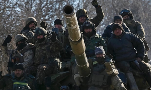Servicemen ride on a tank as they leave Debaltseve.