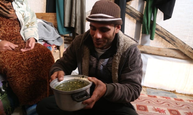 Baby Salma’s uncle with the wild grass soup that makes up the majority of the family’s diet