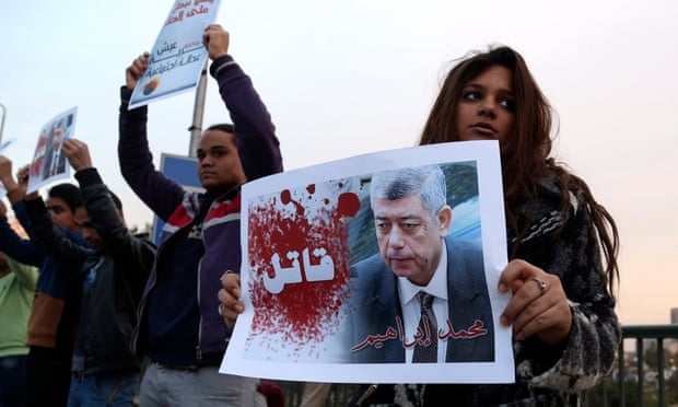 A demonstrator holds a poster of Mohamed Ibrahim with the word "Killer" on it during a silent protest over a bridge in Cairo earlier this month.