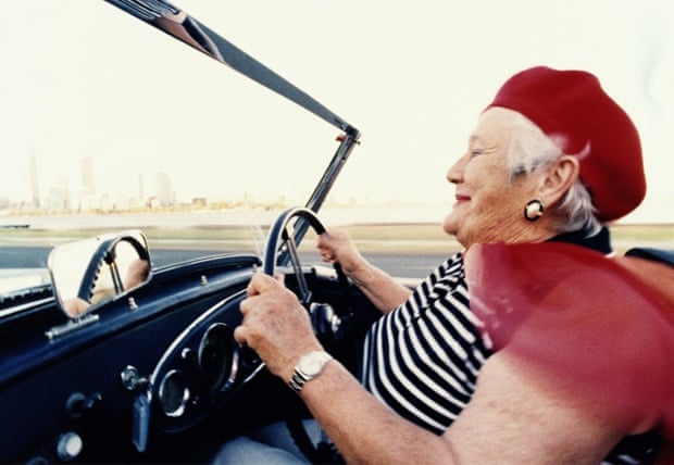 Elderly woman driving convertible sportscar, close-up