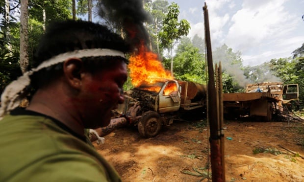 A Ka'apor Indian warrior stands near a burning logging truck in the Alto Turiacu Indian territory, near the Centro do Guilherme municipality in the northeast of Maranhao state in the Amazon basin, August 7, 2014. Tired of what they say is a lack of sufficient government assistance in keeping loggers off their land, the Ka'apor Indians, have sent their warriors out to expel all loggers they find and set up monitoring camps in the areas that are being illegally exploited.
