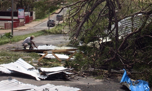 A local resident kneels near debris on a street near damaged homes in Port Vila.