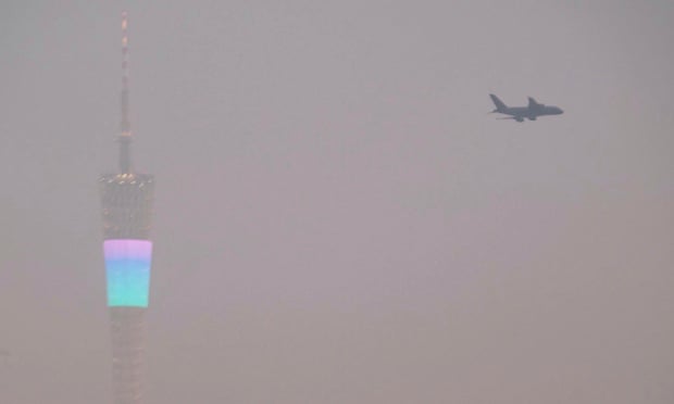 An airplane flies past the Canton Tower (L), or Guangzhou TV Tower, during a hazy day in Guangzhou, Guangdong province January 21, 2015.