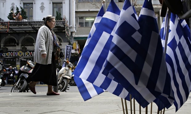 A woman walks past Greek flags for sale in central Athen. Greece is running perilously short of cash