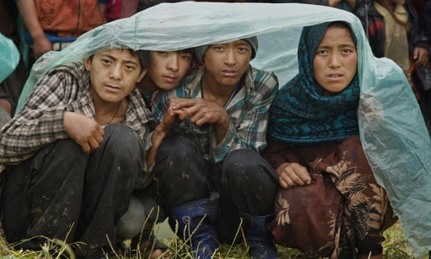 Villagers wait in the rain as an aid relief helicopter lands at their remote mountain village of Gumda, near the epicentre of the quake.