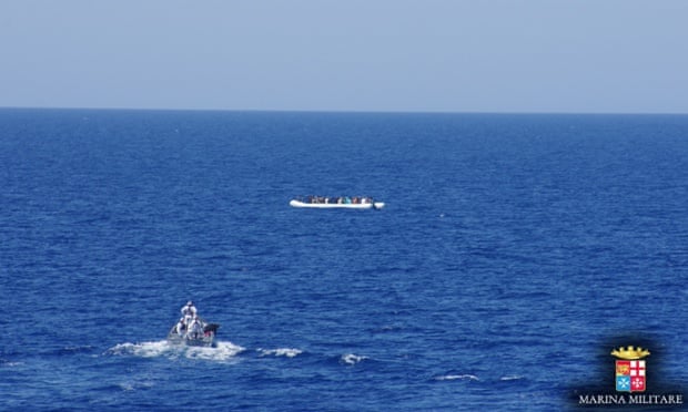 An Italian navy vessel approaches an overloaded dingy carrying migrants.