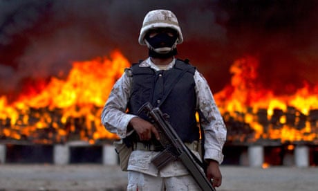 A soldier guards marijuana that is being incinerated in Tijuana, Mexico