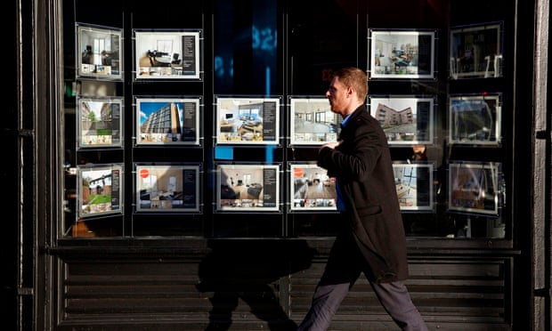 Man walking past an estate agent's window