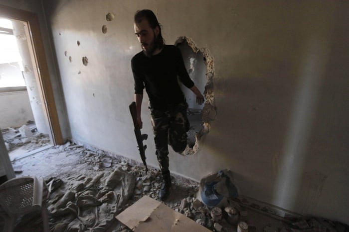 A Free Syrian Army fighter walks through a hole in the wall inside a damaged building on the frontline of Aleppo’s Al-Ezaa neighbourhood.