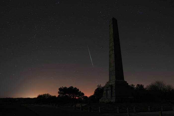 A Geminid meteor streaks across the sky with the Dover Patrol Memorial