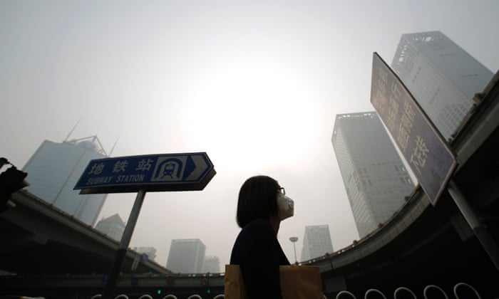 A woman wearing a mask makes her way on a street amid heavy haze and smog in Beijing.