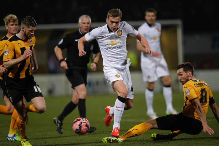 Tom Champion tackles Manchester United's James Wilson as Cambridge United make a solid start.