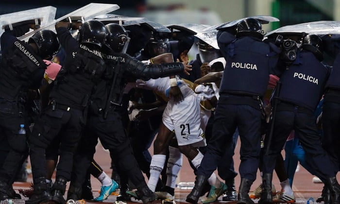 Riot police shield Ghana's John Boye and team-mates from objects thrown by fans.