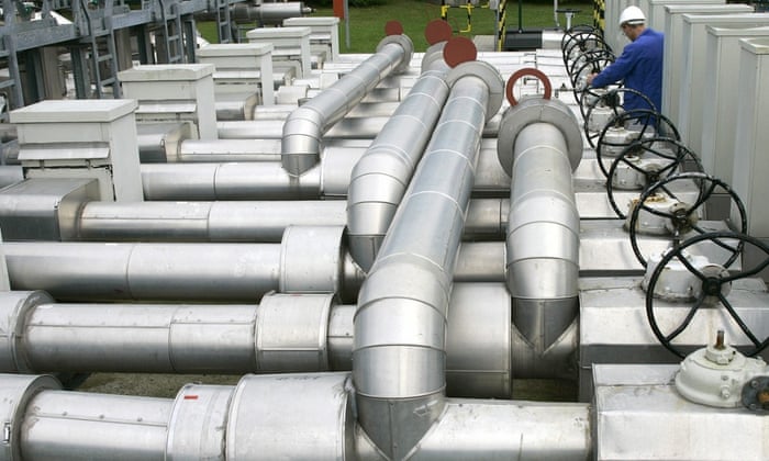 A worker stands between pipes of an oil distribution terminal 