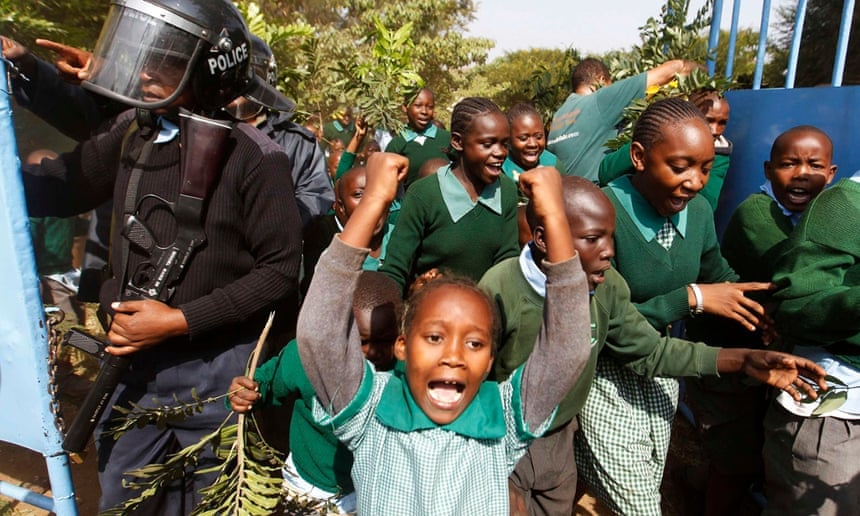 Students from Langata primary school in Nairobi run past riot police as they protest against a perimeter wall illegally erected by a private developer around their school playground in January 2015.