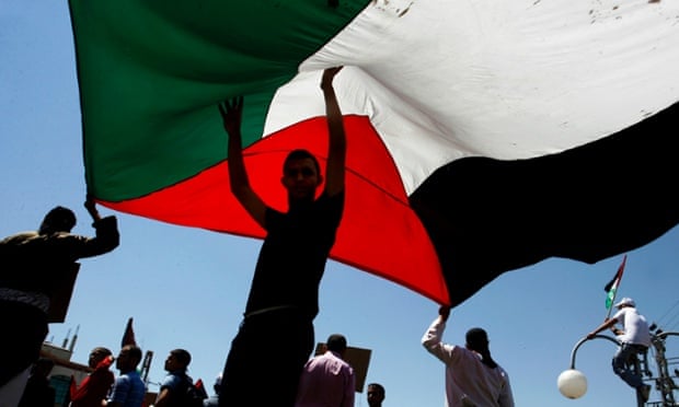 Palestinians hold a large Palestinian flag during a rally in Rafah.