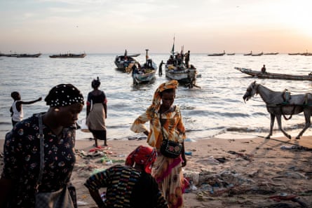 Women wait to buy fish off incoming boats at the fishing port in Mbour, Senegal.