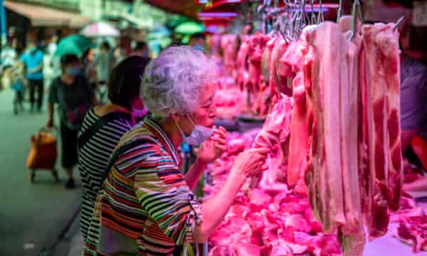 A woman smells the meat before buying at Xihua market in Guangzhou. The shortage of pork after the outbreak of ASF increased demand for other meat in China.