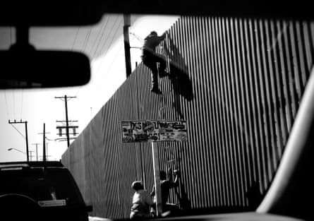 An unidentified man is seen climbing over the international border dividing Mexicali, Mexico, from Calexico, California