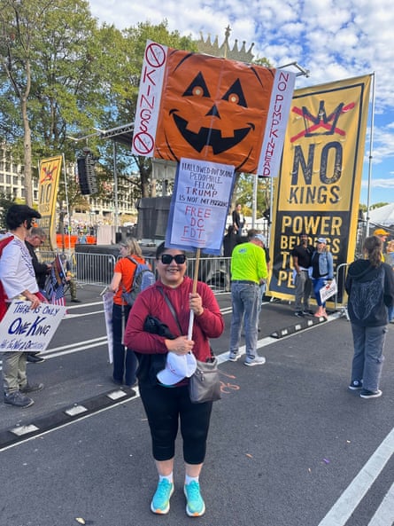 woman at protest holds signs saying ‘Hallow-ed out brain. Pedophile. Felon. Trump is not my president. Free DC FDT’ and ‘No Kings, No Pumpkinhead’