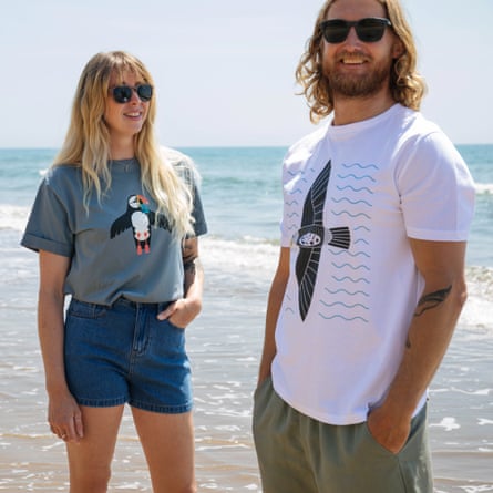 A man and a woman on a sunny beach, wearing t-shirts.