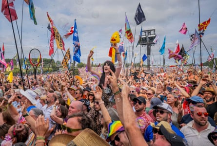 The crowd at Glastonbury festival in 2025, some waving flags and banners